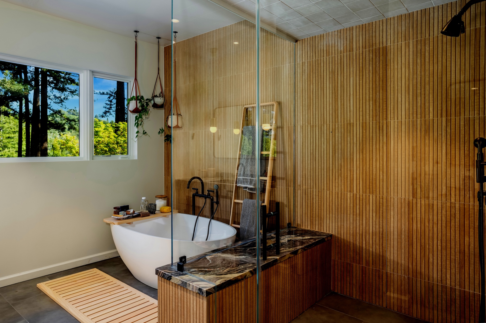 Primary bathroom with wood tub surround and glass shower by M2