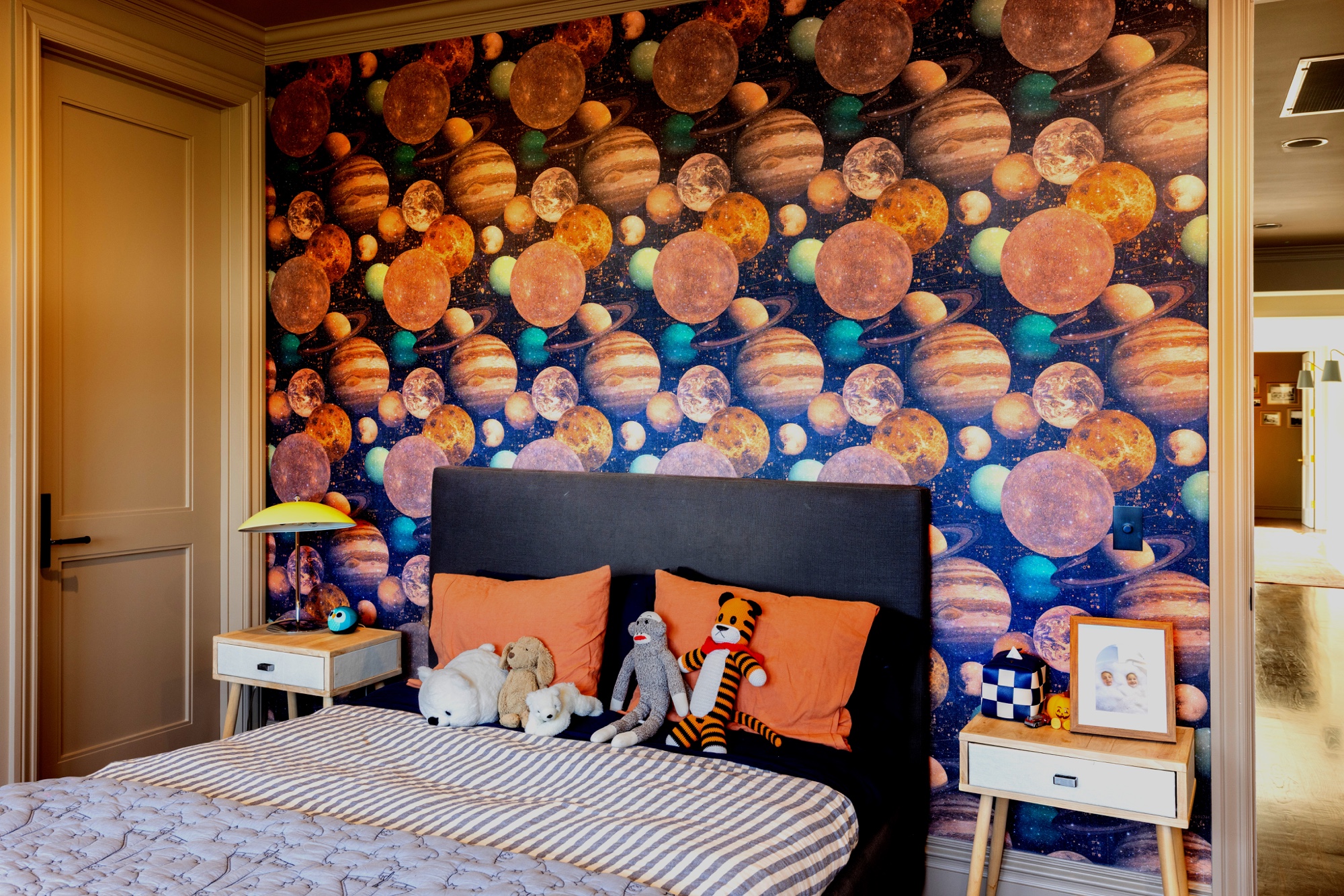 Bedroom with planetary wallcovering, painted trim, and a paneled door